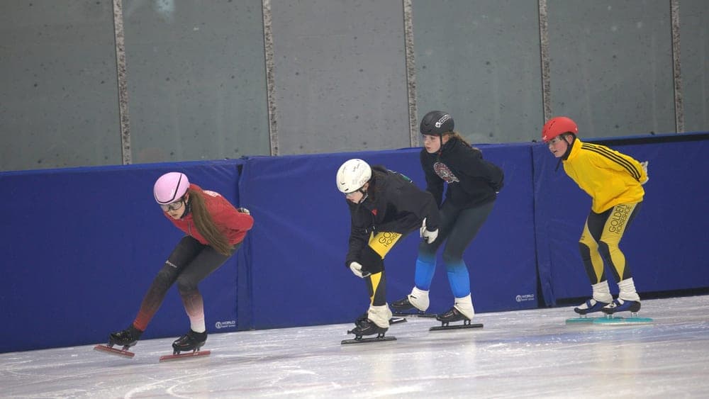 Four older Hamilton speed skaters in training kit at practice.